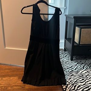 Black sleeveless dress with velvet detail and ruffled trim. Size 0-2